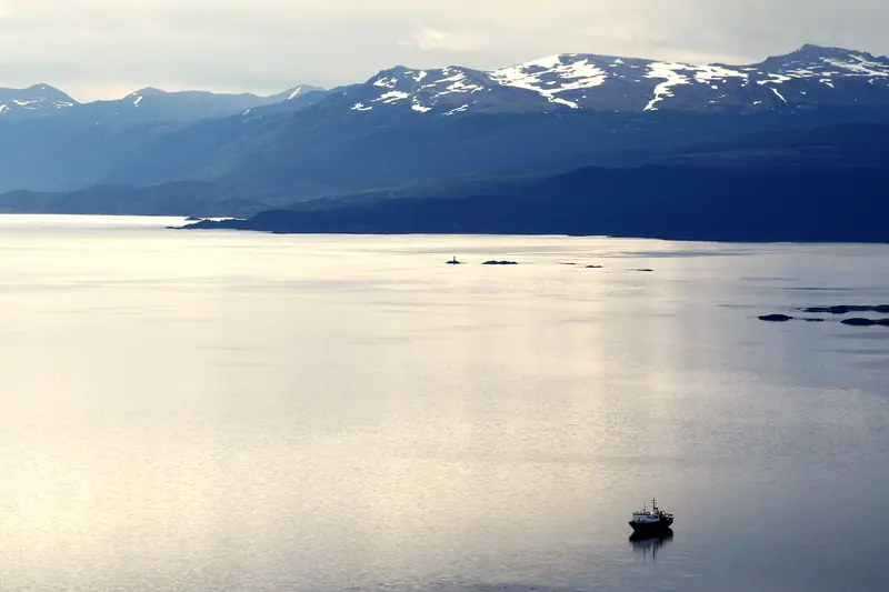 Silver, still water on the Beagle Channel under snow-streaked mountains