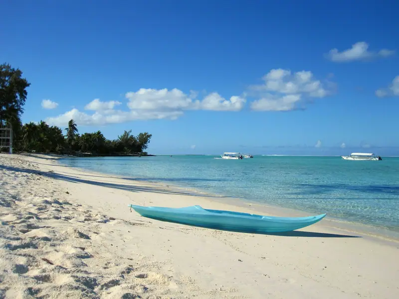 A kayak on white sand beside the turquoise lagoon of Bora Bora, French Polynesia