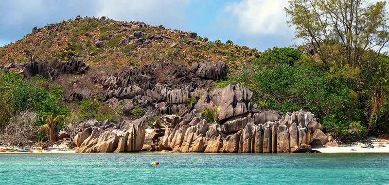 Sculpted granite rocks above turquoise water on the coast of Curieuse Island