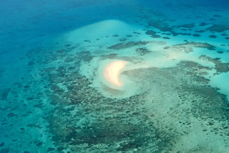 A white sandbar ringed by turquoise water and reef on the Great Barrier Reef, Australia
