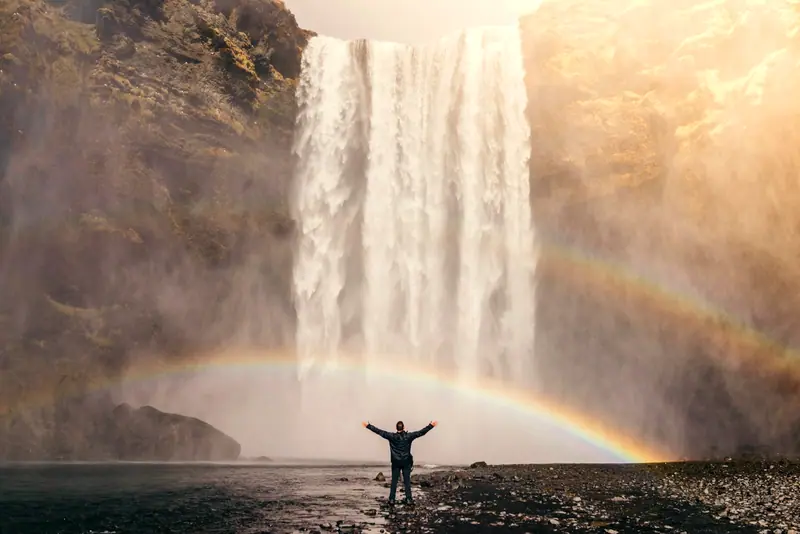 A misty waterfall with a double rainbow in soft light